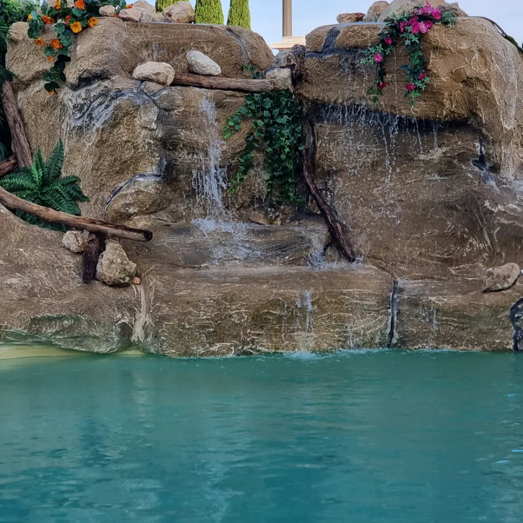 piscine en eau avec rocher artificiel présentant une cascade artificielle