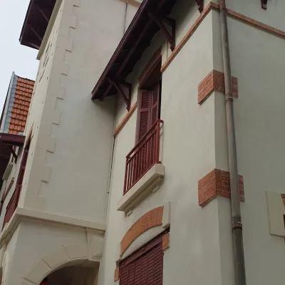 Un bâtiment ayant une façade blanche avec des contour pierre et brique, présentant un style architectural contemporain aux lignes épurées