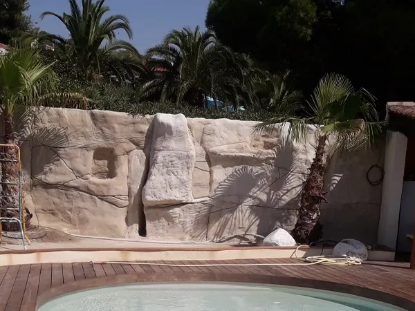 pierre décorative effet naturel sur le mur avec des palmiers devant une piscine