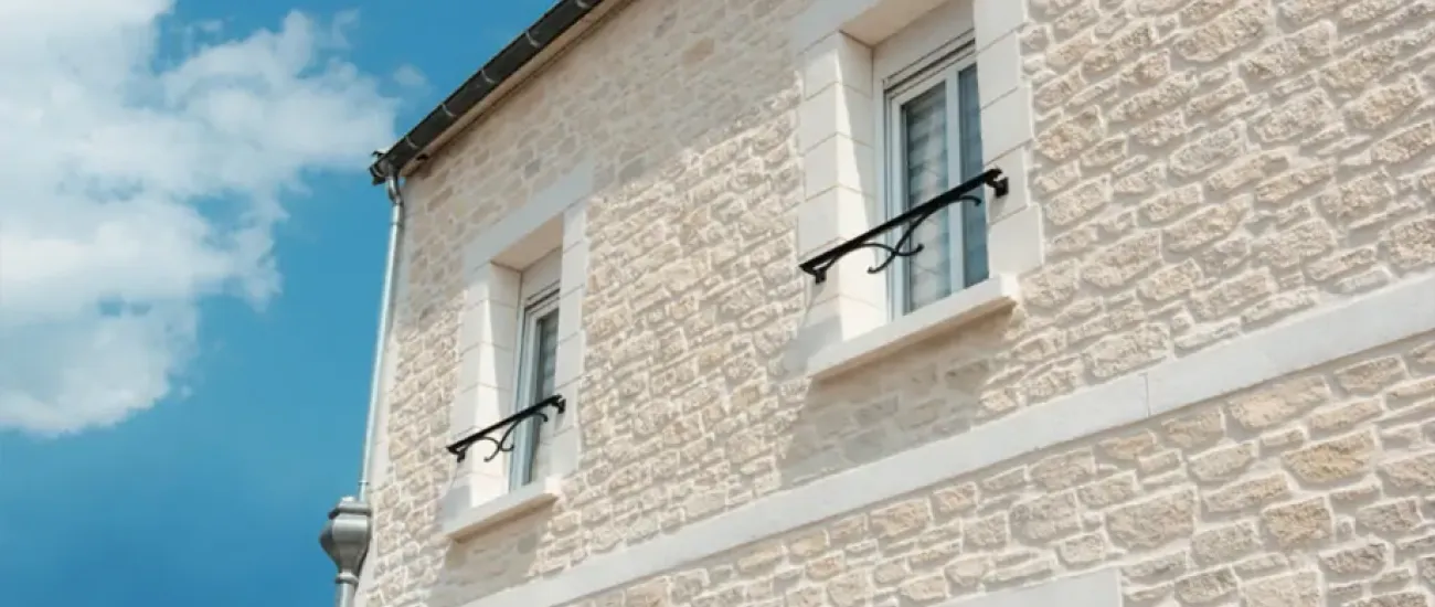 . Un bâtiment blanc avec deux fenêtres, présentant une façade imitation pierre