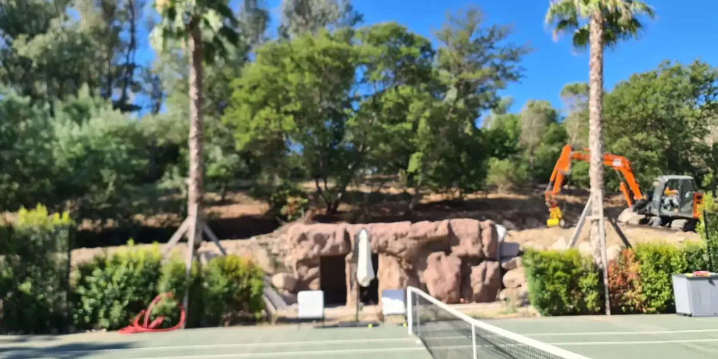 résultat final d'un local technique réalisé en faux rochers artificiel au bord d'un terrain de tennis